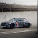 BMW M electric Neue Klasse prototype driving near a test facility during development