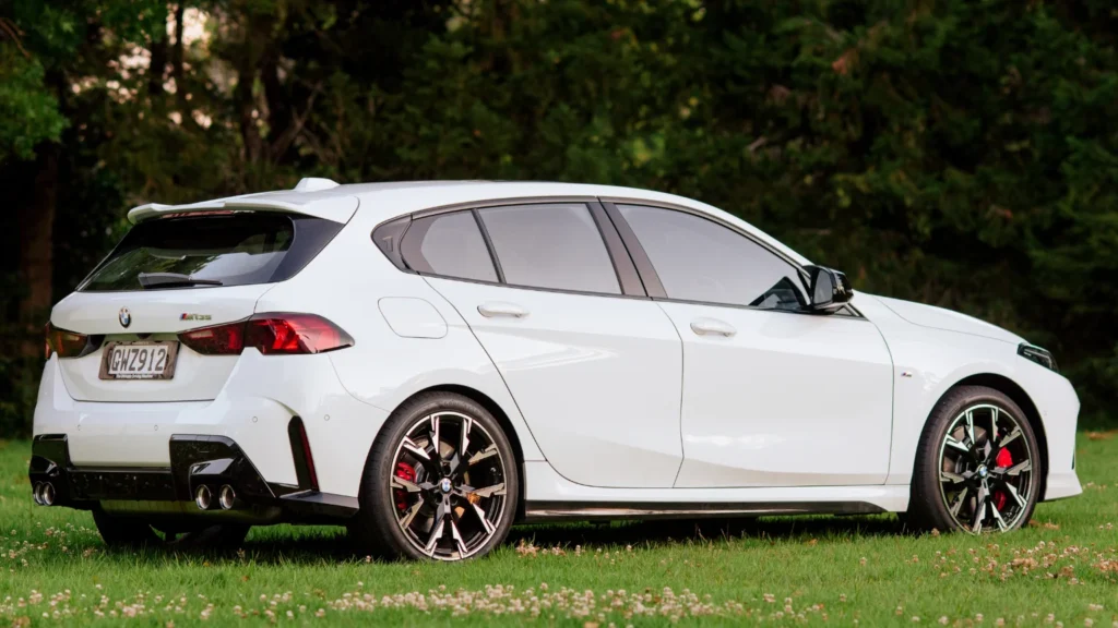 Rear three-quarter view of the BMW M135i showing quad exhaust tips and rear spoiler