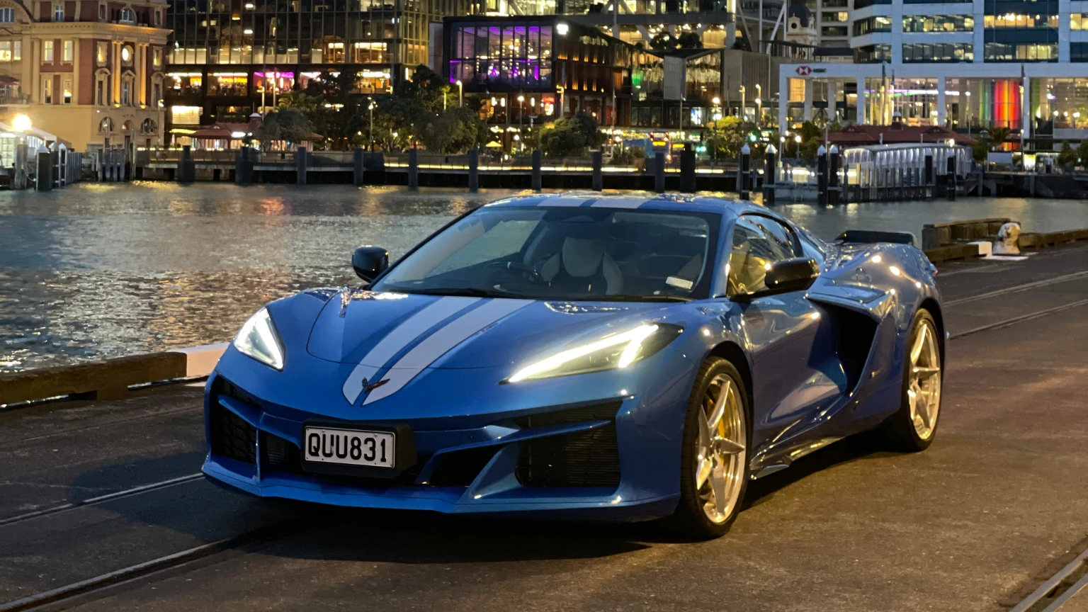 Front three-quarter night view of the Chevrolet Corvette E-Ray parked on a city waterfront