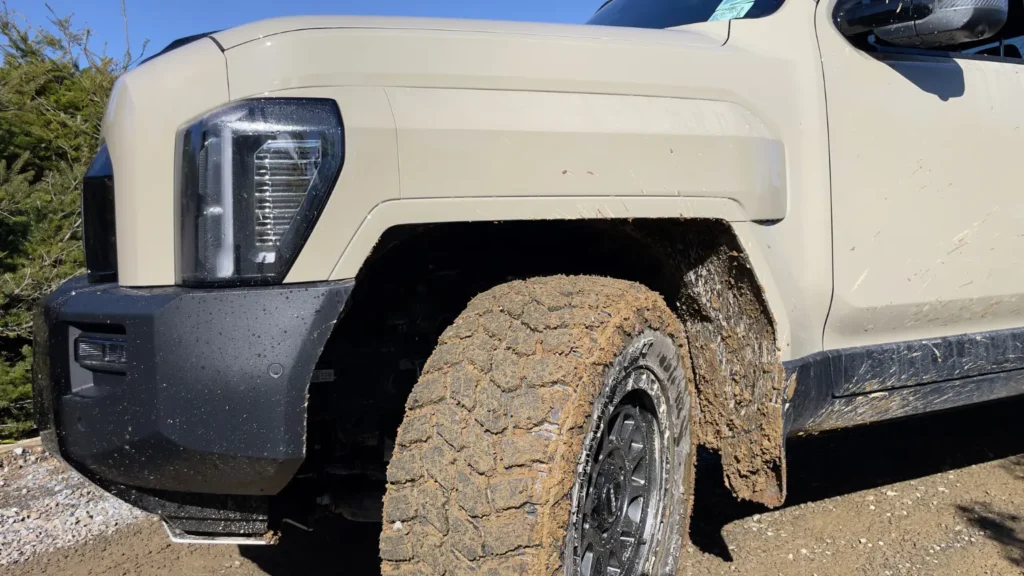Kia Tasman muddy off-road tyres and wheel arch close-up