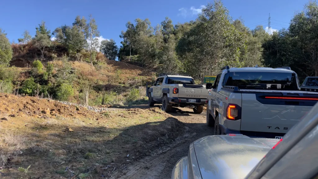 Kia Tasman vehicles driving in convoy on forest off-road track