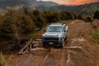 Kia Tasman driving over logs during off-road testing in New Zealand