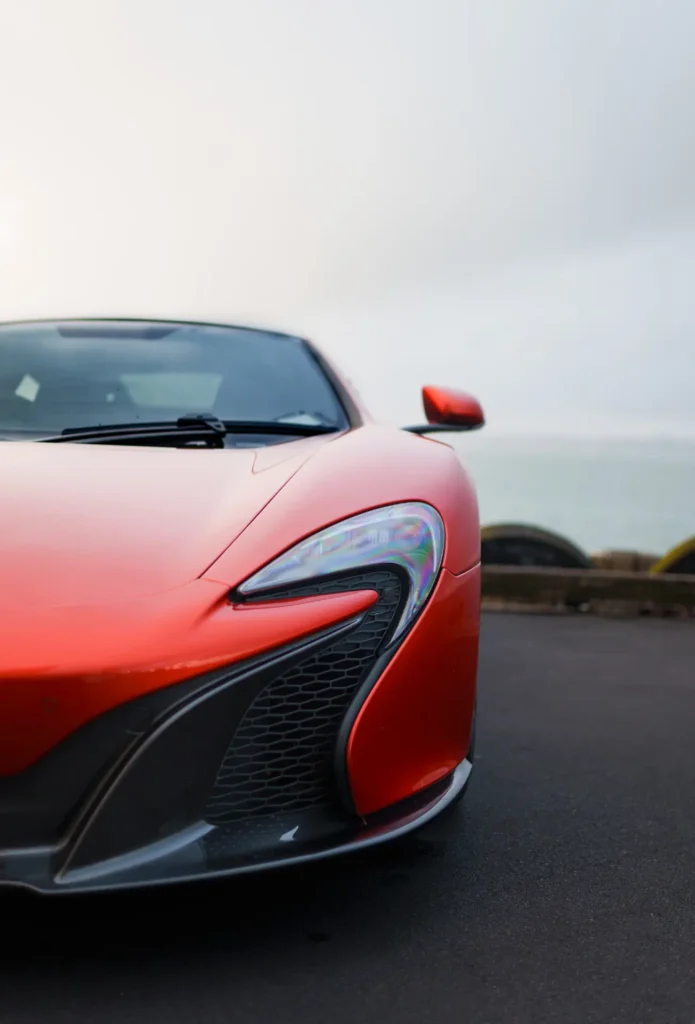 Front quarter view of a red McLaren 650S parked near the coast