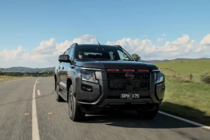 2026 Nissan Navara pickup truck driving on a rural highway with mountains and blue sky in background