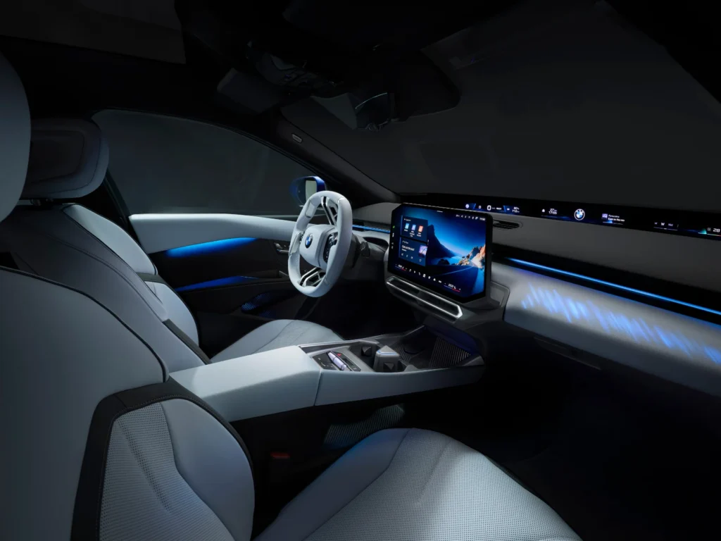 BMW i3 Panoramic iDrive dashboard with large touchscreen display and ambient blue lighting at night