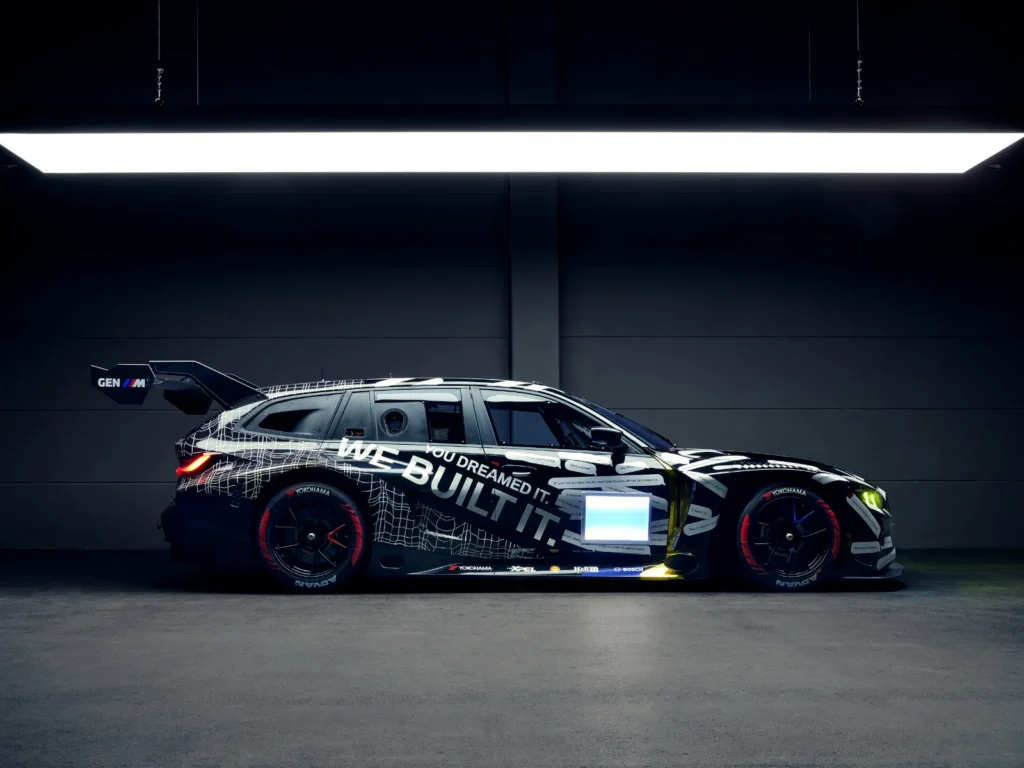 BMW M3 Touring race car side view in a studio with “We Built It” livery and large rear wing