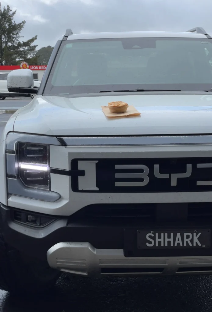 BYD Shark 6 front view with pie on hood unique lifestyle shot