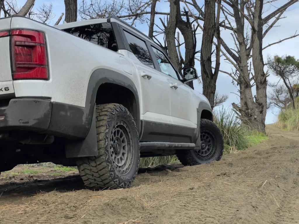BYD Shark 6 climbing rough off-road terrain rear side view